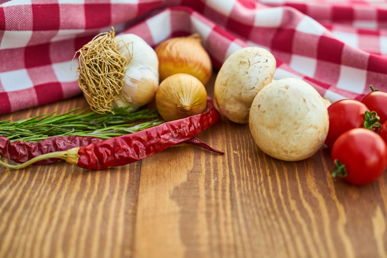 Garlic, tomatoes, herbs, mushrooms, and peppers on a work table